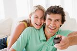 Couple in living room holding remote control smiling