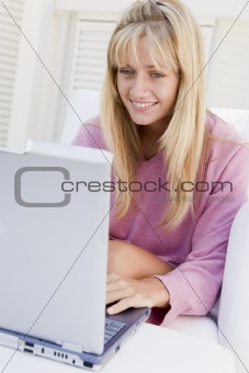 Woman on patio using laptop smiling