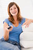 Woman in living room with remote control smiling