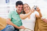 Couple in living room with digital camera smiling