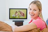 Woman in living room watching television smiling