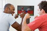 Two men in living room watching television and cheering