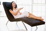Woman sitting in chair using remote control smiling