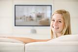 Woman in living room watching television smiling