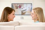 Two women in living room watching television smiling