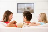 Three friends in living room watching television smiling
