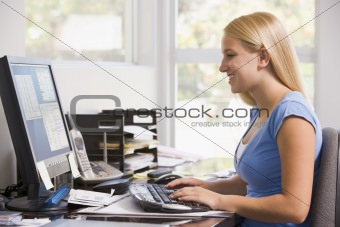 Woman in home office using computer and smiling