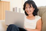 Woman in living room using laptop and smiling