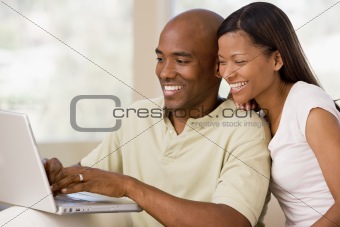 Couple in living room using laptop and smiling