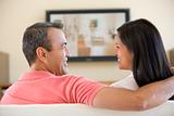 Couple in living room watching television smiling