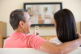 Couple in living room watching television laughing