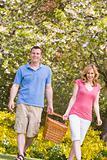 Couple walking outdoors with picnic basket smiling