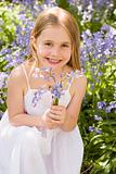 Young girl outdoors holding flowers smiling