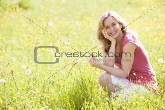 Woman outdoors holding flower smiling