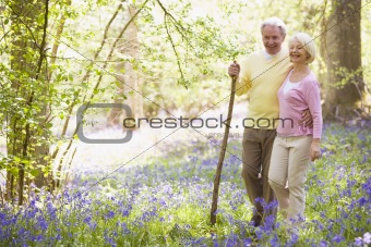 Couple walking outdoors with walking stick smiling