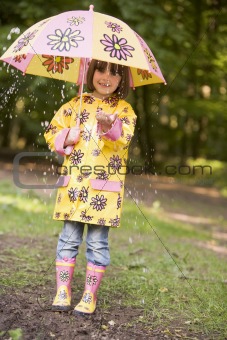 Young girl outdoors in rain with umbrella smiling