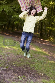 Woman outdoors jumping with umbrella smiling