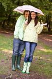 Couple outdoors in rain with umbrella smiling