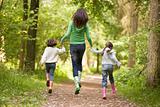 Mother and daughters skipping on path smiling