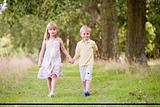 Two young children walking on path holding hands smiling