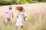 Three young children running outdoors