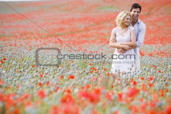 Couple in poppy field embracing and smiling