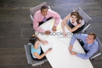 Four businesspeople at boardroom table smiling
