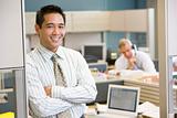 Businessman standing in cubicle smiling