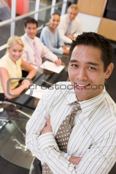 Businessman with four businesspeople at boardroom table in backg