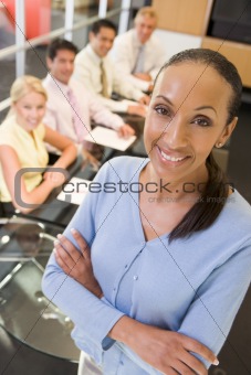 Businesswoman with four businesspeople at boardroom table in bac