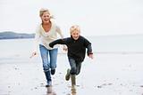 Mother and son running on beach smiling