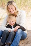 Mother and son sitting on beach smiling