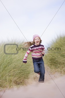 Young girl running on beach smiling