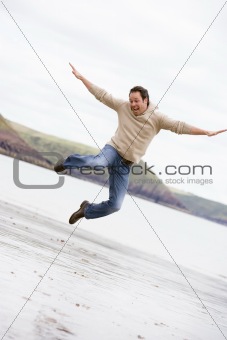 Man jumping on beach smiling