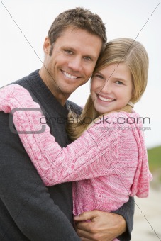 Father holding daughter at beach smiling