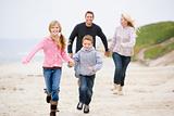 Family running at beach holding hands smiling