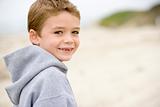 Young boy standing on beach smiling