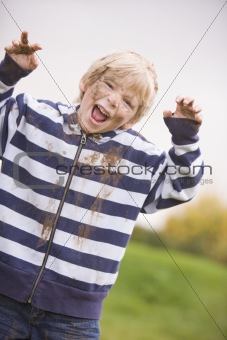 Young boy standing outdoors dirty and smiling