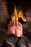 Father and son's feet warming at a fireplace
