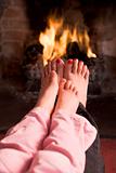 Mother and daughter's Feet warming at a fireplace