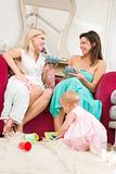 Two mothers in living room with babies and coffee smiling