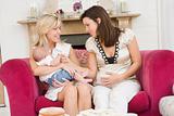 Two mothers in living room with baby and cake smiling