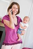 Mother in living room using telephone holding baby smiling