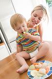 Mother and baby in kitchen eating fruit and vegetables