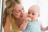 Mother and baby in kitchen eating apple