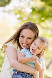 Mother holding daughter outdoors smiling