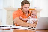 Father and baby in dining room with laptop