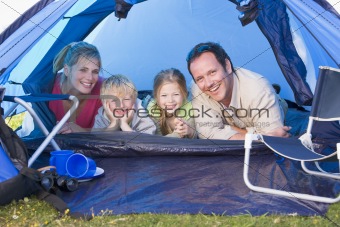 Family camping in tent smiling