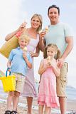 Family standing at beach with ice cream smiling