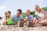 Family on beach making sand castles smiling